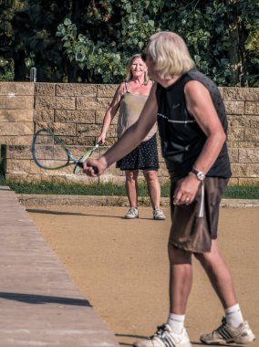Bükreş / Romanya - 09.19.2020: Yaşlı çift parkta tenis oynuyor. Arka plandaki bayana odaklan..