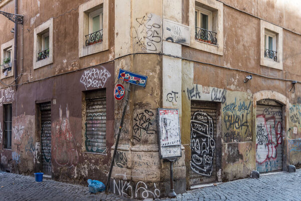 a corner of the old part of the city, the walls are painted, dirty with rubbish and with a folded traffic sign