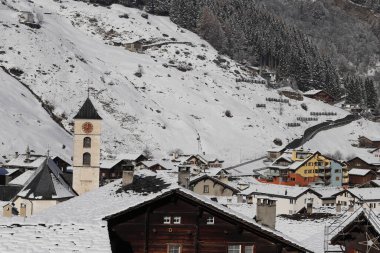 İsviçre 'de altın kırmızısı saati olan bir kilise. Arka planda kış manzarası.