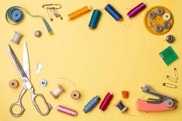 Composição com fios e acessórios de costura - tesoura, centímetro, alfinetes em fundo amarelo . — Fotografia de Stock