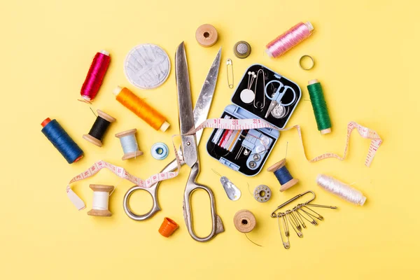 Composition with threads and sewing accessories - scissors, centimeter, pins on yellow background. — Stock Photo, Image