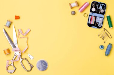 Kompozisyon konuları ve dikiş aksesuarları - makas, santimetre, sarı zemin üzerine iğne.