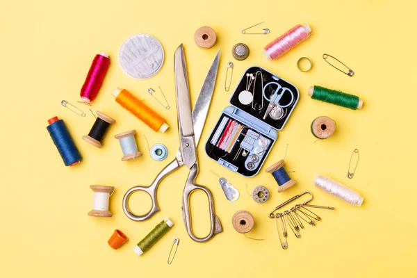 Composition with threads and sewing accessories - scissors, centimeter, pins on yellow background. — Stock Photo, Image