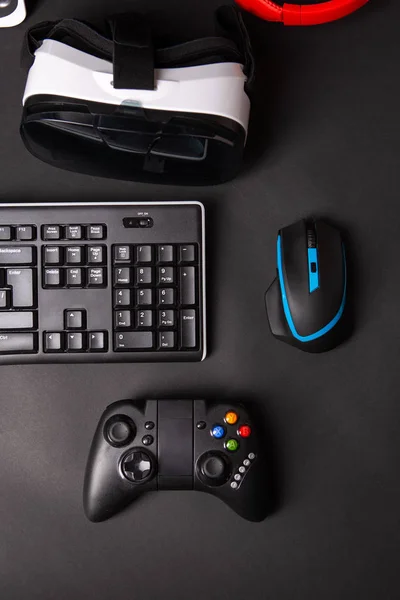 Pohled shora, herní zařízení, myš, klávesnice, joystick, sluchátka, Vr Headset na pozadí černý stůl. — Stock fotografie