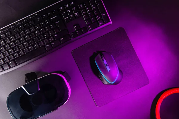 Top view a gaming gear, mouse, keyboard, joystick, headset, VR Headset on black table background.