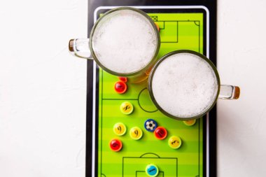 Resminin üst kısmında iki bardak köpüklü bira, Masa futbolu