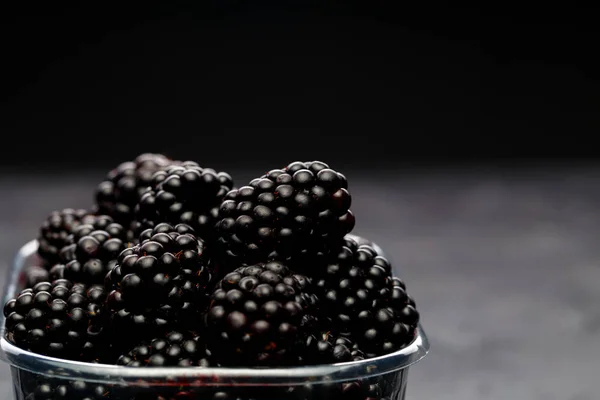 Image of blackberry in plastic container on empty black background. — Stock Photo, Image
