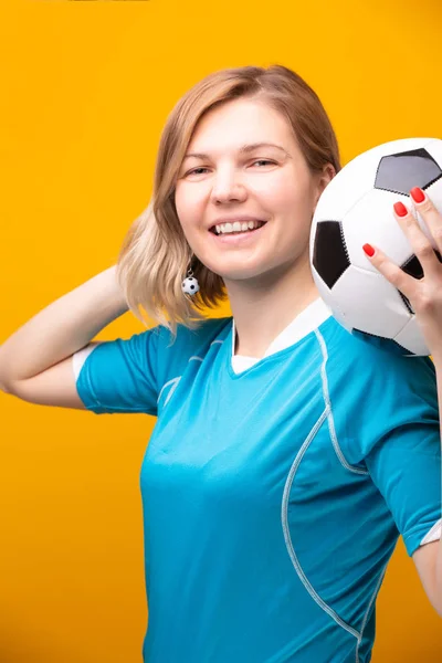 金髪の女性は黄色の背景にサッカー ボールの写真 — ストック写真