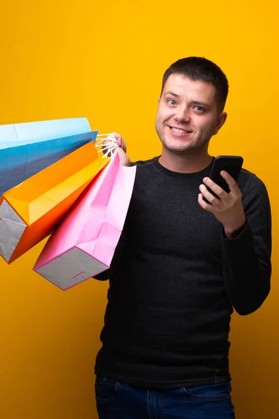 Φωτογραφία του ανθρώπου με τηλέφωνο και πολύχρωμες τσάντες για ψώνια — Φωτογραφία Αρχείου