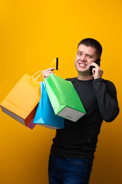 Foto des Mannes mit Papiertüten, Bankkarte und Handy in der Hand — Stockfoto