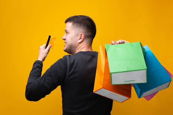 Foto de hombre con tarjeta bancaria y bolsas de compras multicolores — Foto de Stock