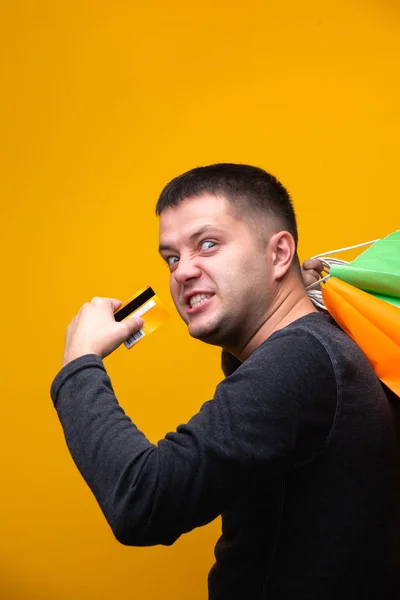 Photo de l'homme avec carte bancaire et sacs à provisions multicolores — Photo