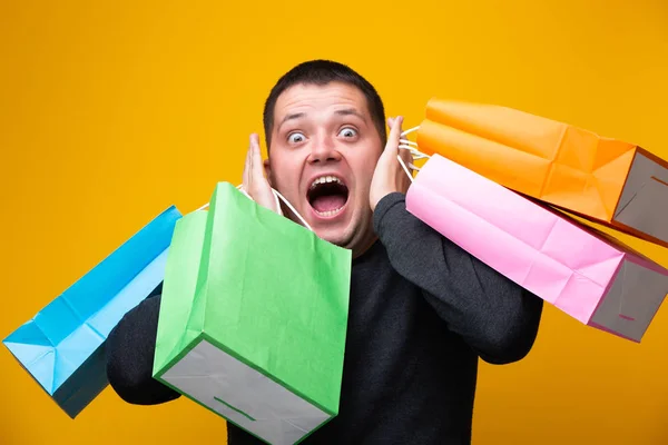 Imagem de homem surpreso com sacos de compras no fundo laranja — Fotografia de Stock