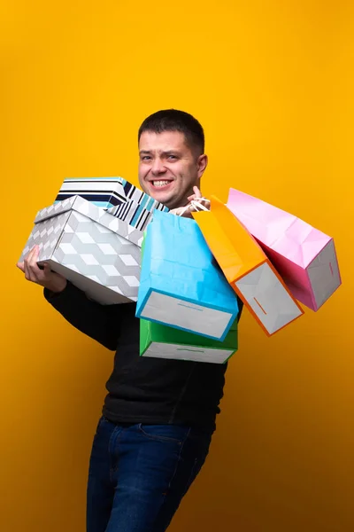 Photo of male shopper with paper bags and boxes