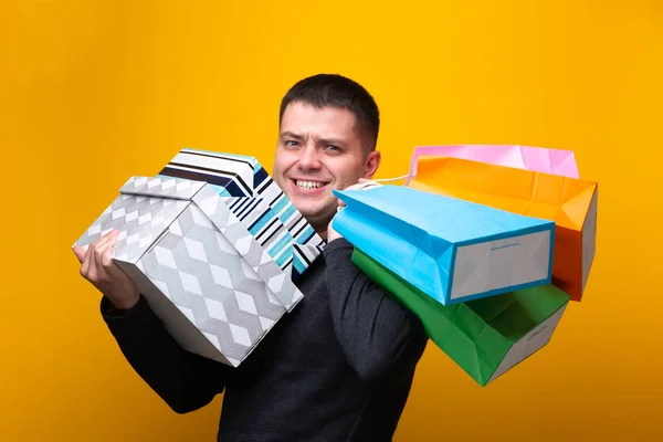 Photo of happy male shopper with paper bags and boxes