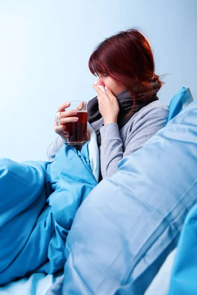 Foto av sjuka brunett med kopp te sittande i sängen. — Stockfoto