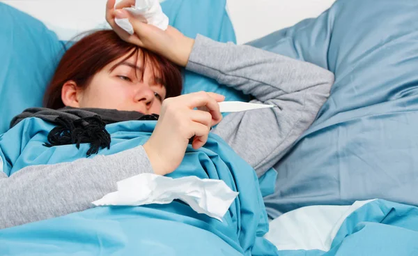 Foto de mulher doente com termômetro deitado na cama . — Fotografia de Stock