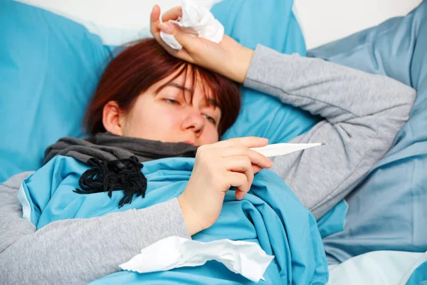 Foto einer kranken Frau mit Thermometer auf dem Bett liegend. — Stockfoto