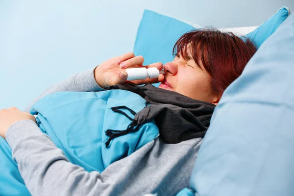 Φωτογραφία του άρρωστη γυναίκα χρήση ρινικών σπρέι ξαπλωμένος στο κρεβάτι — Φωτογραφία Αρχείου
