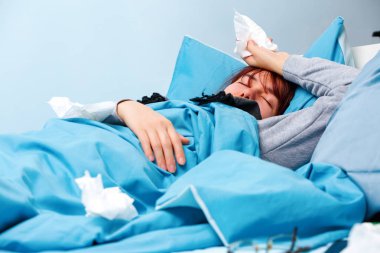 Yatakta yatarken kağıt mendiller ile hasta kadın fotoğrafı