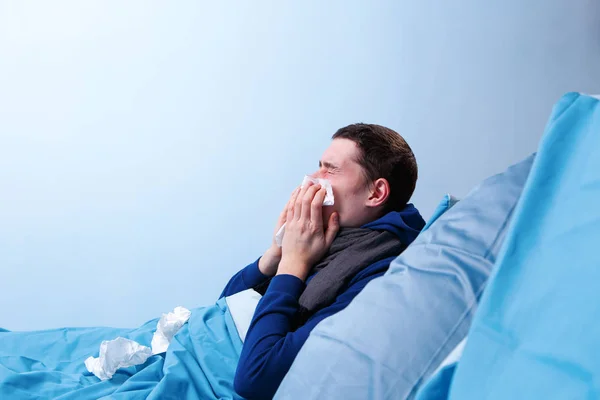 Foto de lado do homem doente com lenço sentado na cama — Fotografia de Stock