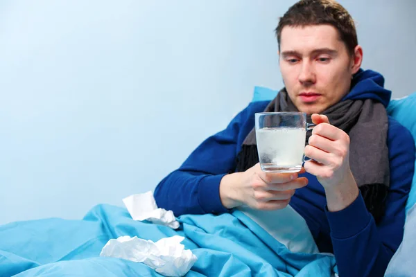 Foto de hombre enfermo en bufanda con taza acostado en la cama —  Fotos de Stock