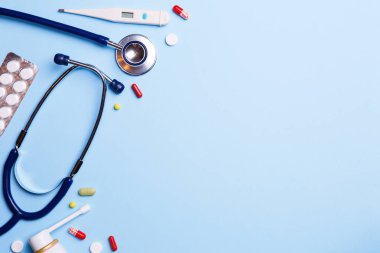 Soğuk algınlığı ilacı, termometre ve mavi bir arka plan üzerinde phonendoscope.