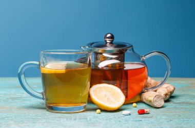 Ahşap mavi arka planda soğuk ilaçlar, çay, limon ve zencefil