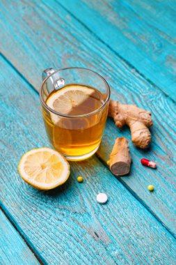 Ahşap mavi arka planda soğuk ilaçlar, çay, limon ve zencefil