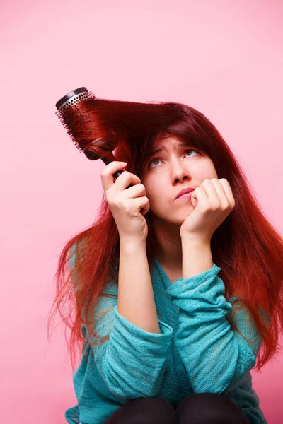 Vrouw borstelen haar haar op roze achtergrond — Stockfoto