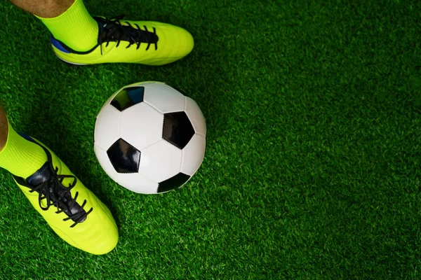 Buty piłkarskie i piłka na zielonej trawie. — Zdjęcie stockowe