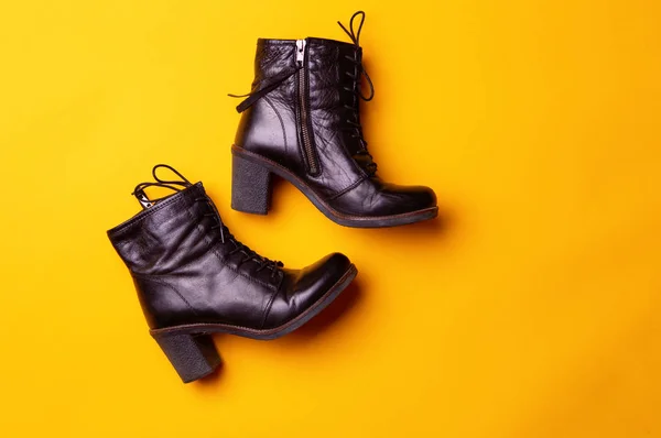 Elegant women black heeled boots. Top view of black boots on a yellow background. — Stock Photo, Image