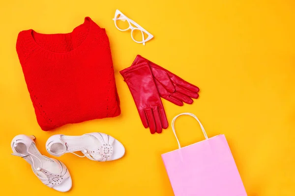 Top view of red swether, stylish shoes, red gloves, white glasses and pink shopping bag