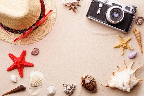 Accesorios de playa - gafas de sol, sombrero y cámara en conchas de arena witn y mar . — Foto de Stock