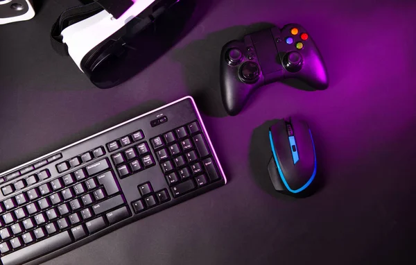 Top view a gaming gear, mouse, keyboard, joystick, headset, VR Headset on black table background.