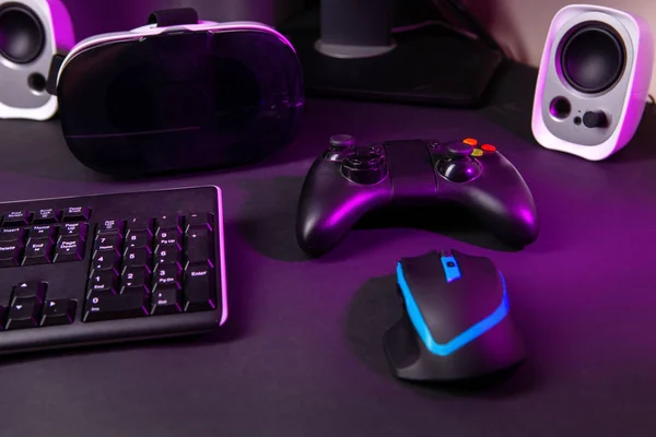 Top view a gaming gear, mouse, keyboard, joystick, headset, VR Headset on black table background.