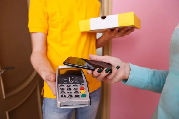 Woman pays for pizza phone to courier via pin pad — Stock Photo, Image