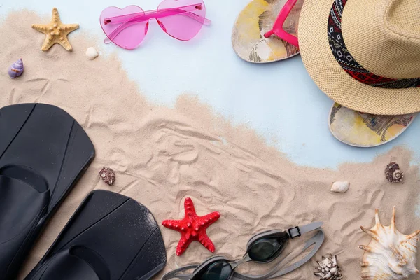 Gafas de natación, aletas, chanclas, gafas de sol y sombrero en la arena con conchas y estrellas de mar . — Foto de Stock