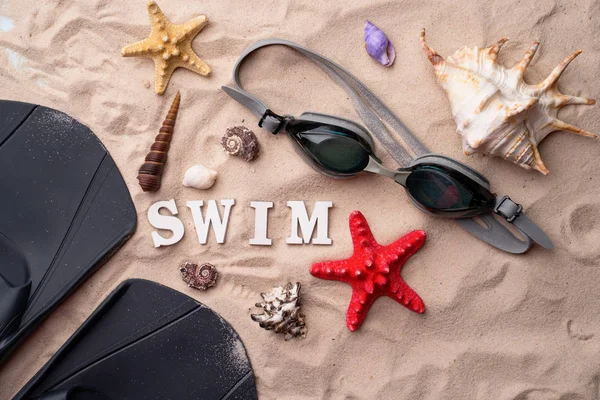 Gafas de natación y aletas en la arena con conchas y estrellas de mar . — Foto de Stock
