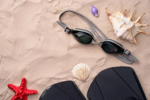 Gafas de natación y aletas en la arena con conchas y estrellas de mar . —  Fotos de Stock