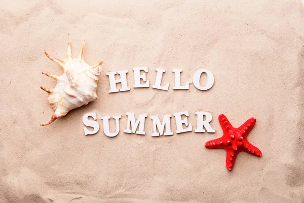Text Hello léto z bílých a mořských mušle a hvězdných ryb na písku. — Stock fotografie