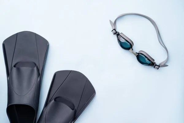 Svømmebriller og svømmeføtter på blå bakgrunn . – stockfoto