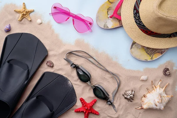 Gafas de natación, aletas, chanclas, gafas de sol y sombrero en la arena con conchas y estrellas de mar . — Foto de Stock