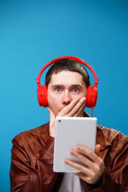 Adam tablet bilgisayar kullanıyor ve kulaklıkla müzik dinliyor.