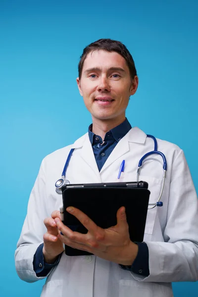 Portrait of doctor with stethoscope and tablet computer in hand on blue background — Stock Photo, Image