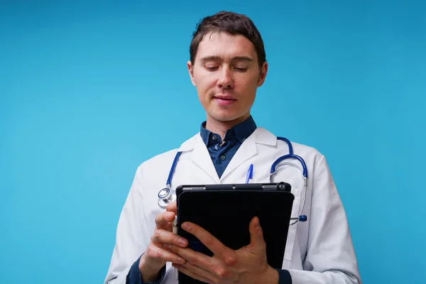 Retrato del médico con estetoscopio y tableta en la mano sobre fondo azul —  Fotos de Stock