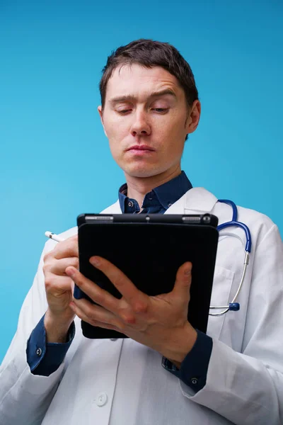 Portrait of doctor with stethoscope and tablet computer in hand on blue background — Stock Photo, Image