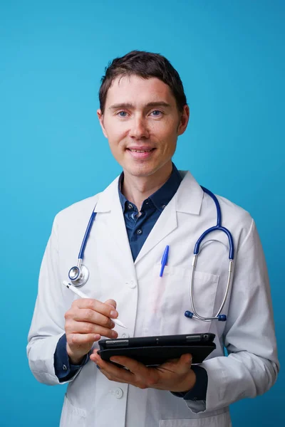 Portrait of doctor with stethoscope and tablet computer in hand on blue background — Stock Photo, Image