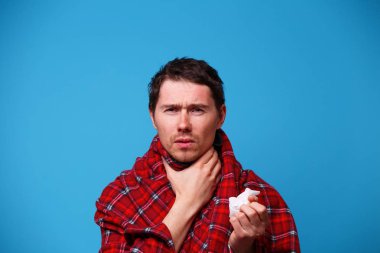 Battaniyeye sarılmış hasta adam boğazını tutuyor. Boğaz ağrısı kavramı