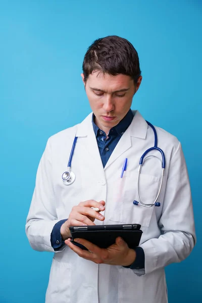 Portrait of doctor with stethoscope and tablet computer in hand on blue background — Stock Photo, Image